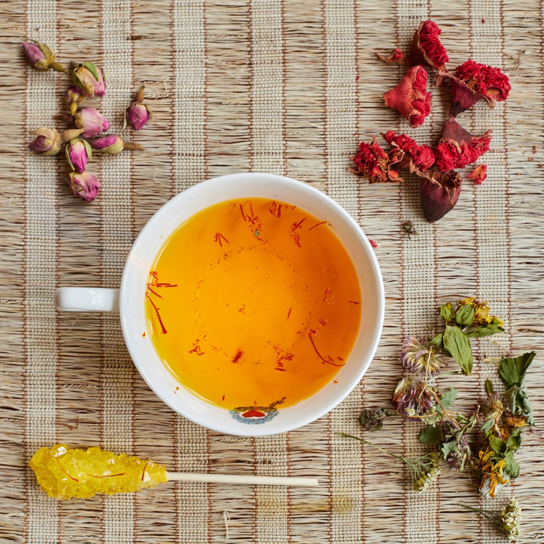 Cup of herbal tea with scattered herbs viewed from above