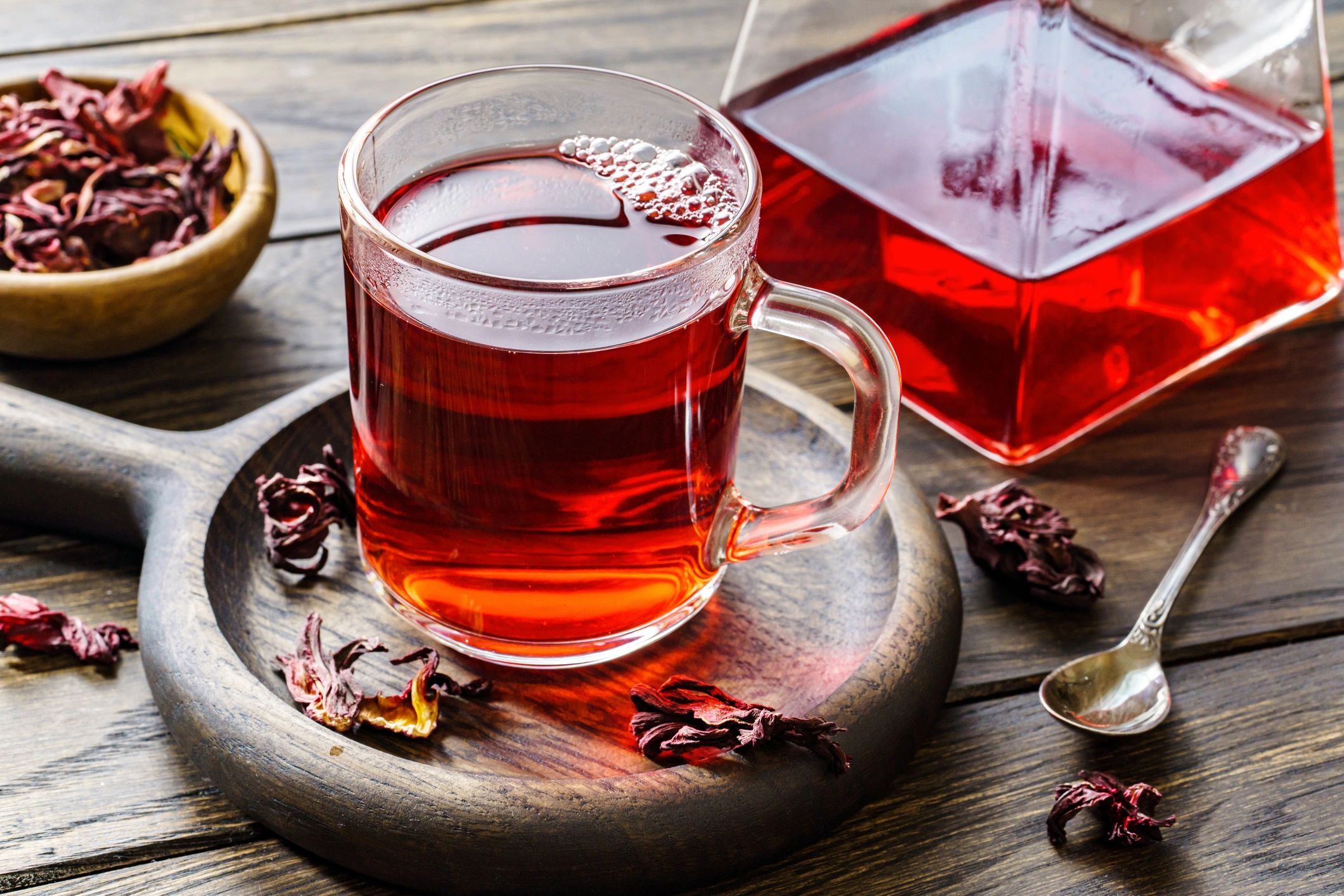 Glass cup and teapot of hot hibiscus tea on a wooden table