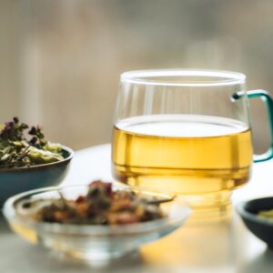 A cup of tea with dry fruit, flowers, and herbs.