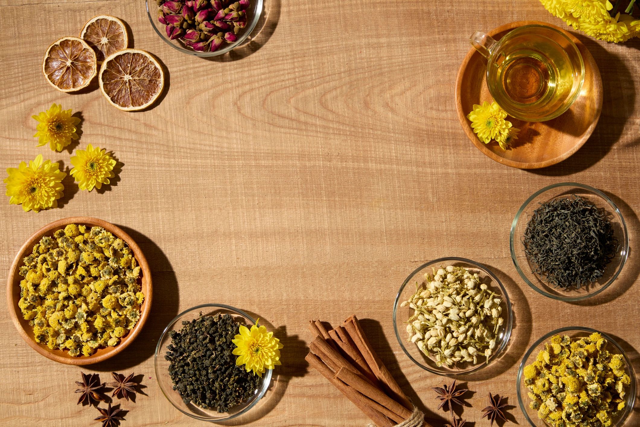 Cinnamon sticks and dried herbs with tea on a wooden surface, top-down